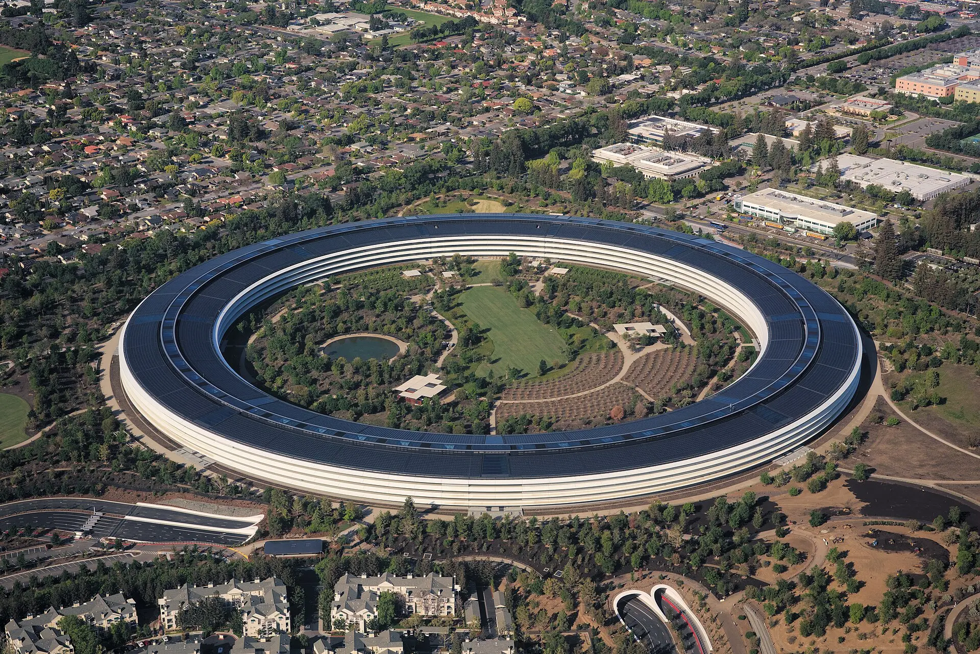 Vista aérea do Apple Park, sede circular da Apple em Cupertino, cercada de vegetação.